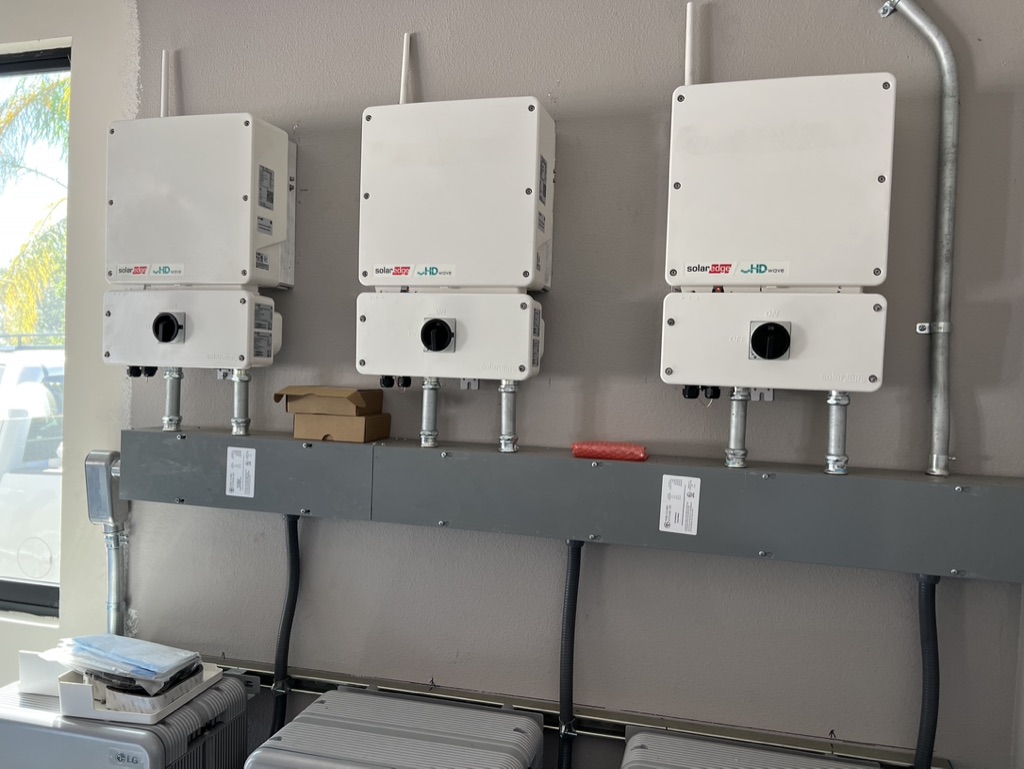 Three SolarEdge HD-Wave inverters above LG home battery storage in a garage