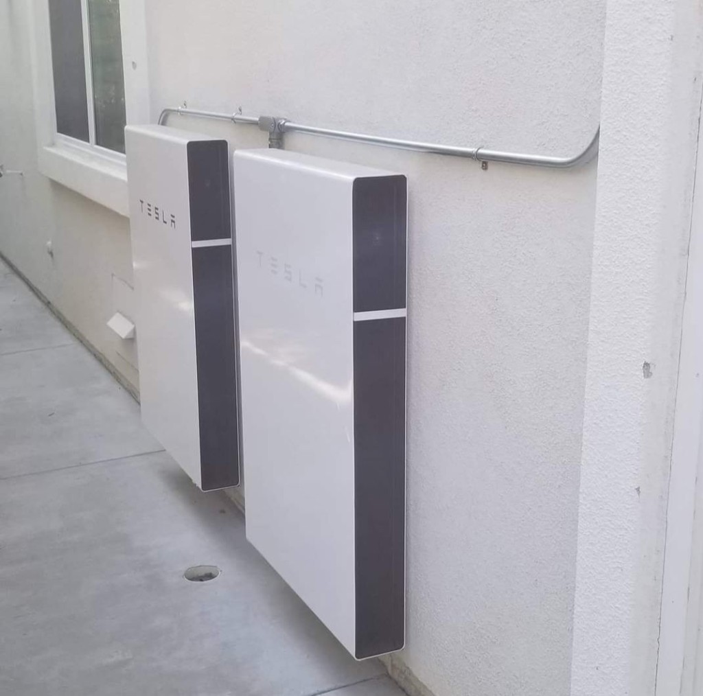 Two Tesla Powerwall batteries mounted on an exterior stucco wall