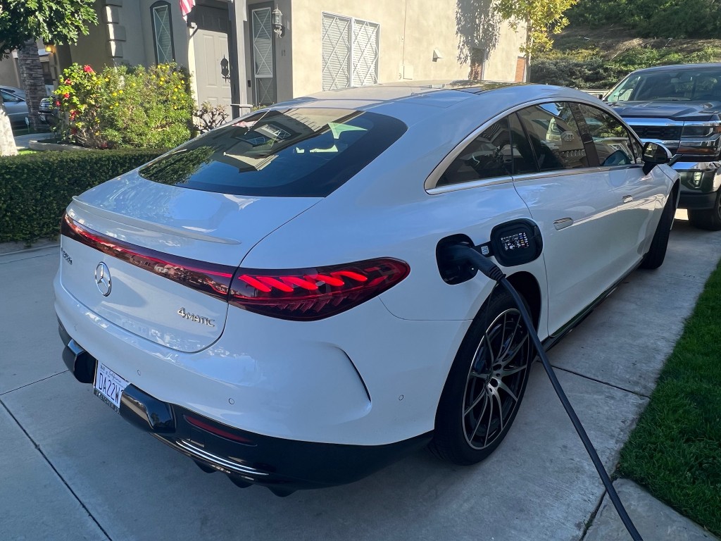 White Mercedes-Benz EQ sedan charging in a residential driveway