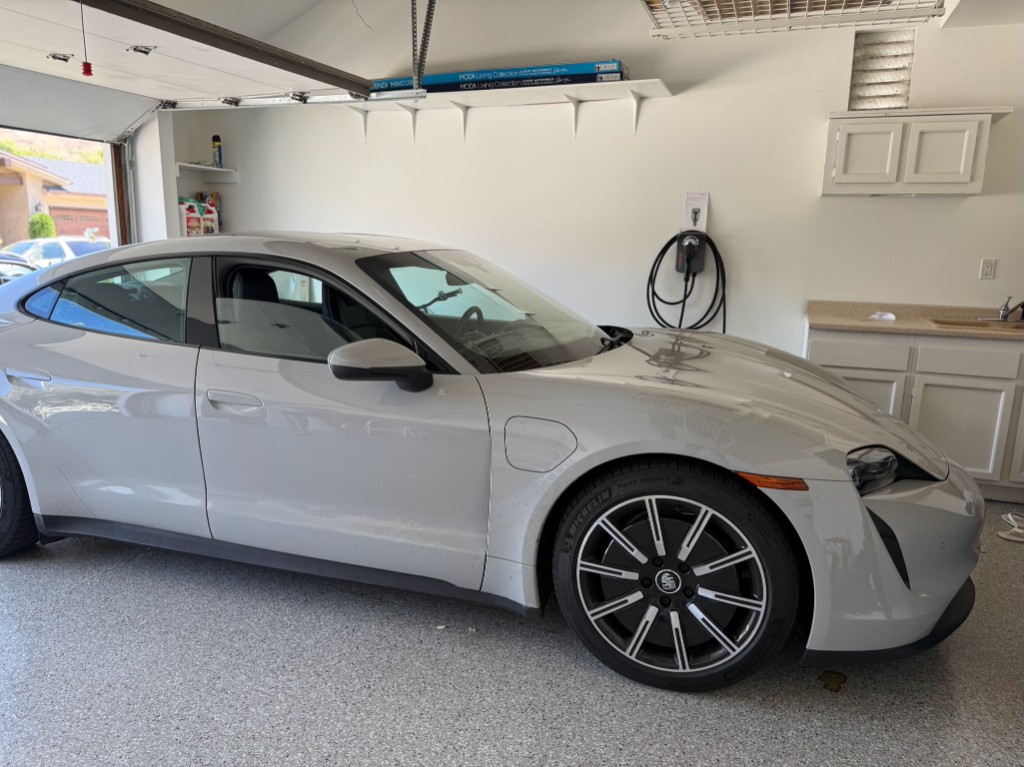 Porsche Taycan parked in a garage with a wall-mounted EV charger