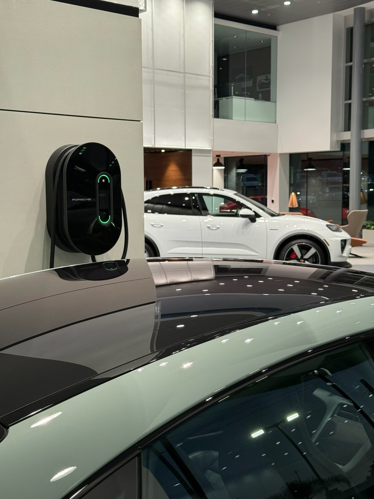 Porsche EV charger installed on a wall inside a Porsche dealership showroom